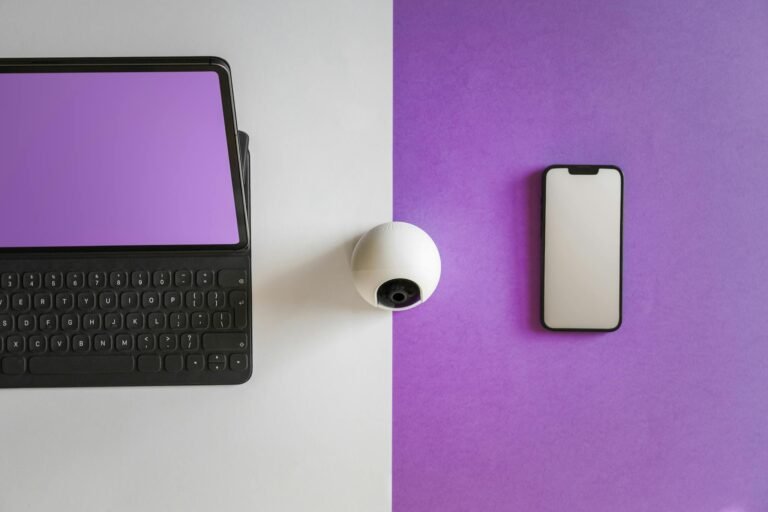 Minimalist setup featuring a tablet, smartphone, and spherical webcam on a split colored background.